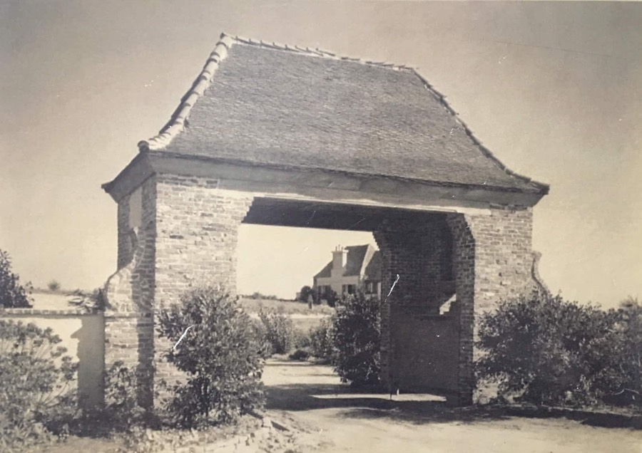 The original St. Malo gatehouse in sepia, a cottage visible through the arch