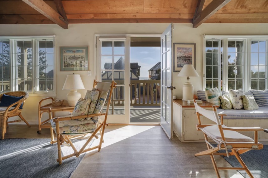 The ocean-facing room, French doors open to the balcony and the Pacific beyond