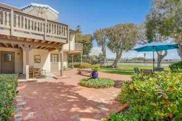 Brick patio with teal umbrellas opening to the lagoon lawn
